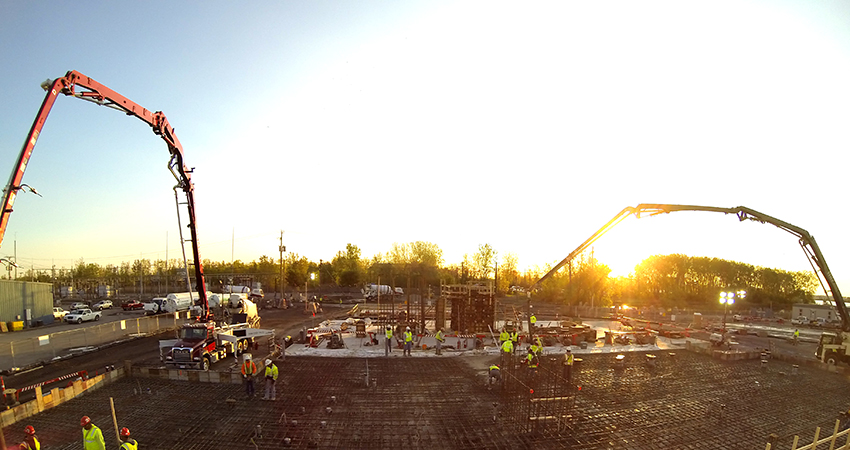 job site where concrete pour is taking place, cranes in background